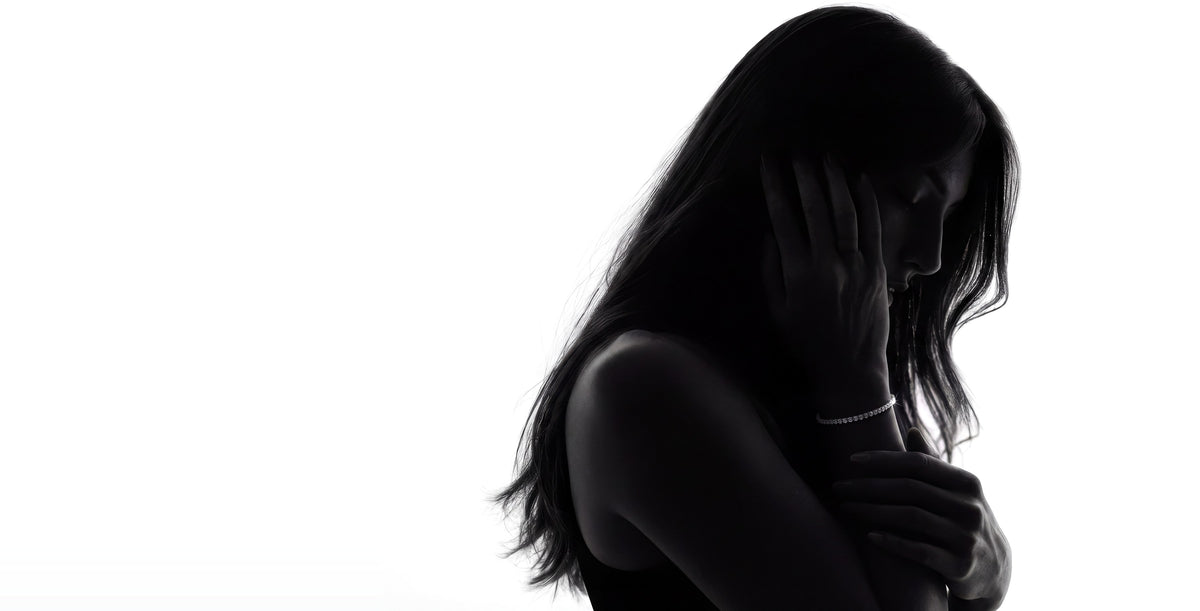 Silhouette of a woman with her hand at her cheek, wearing a 2mm lab-grown moissanite tennis bracelet