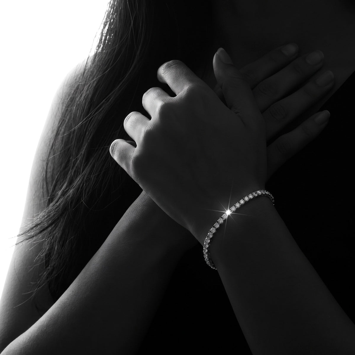 Hands folded against the chest, one wrist wearing a 2mm lab-grown moissanite tennis bracelet (illustrative render)