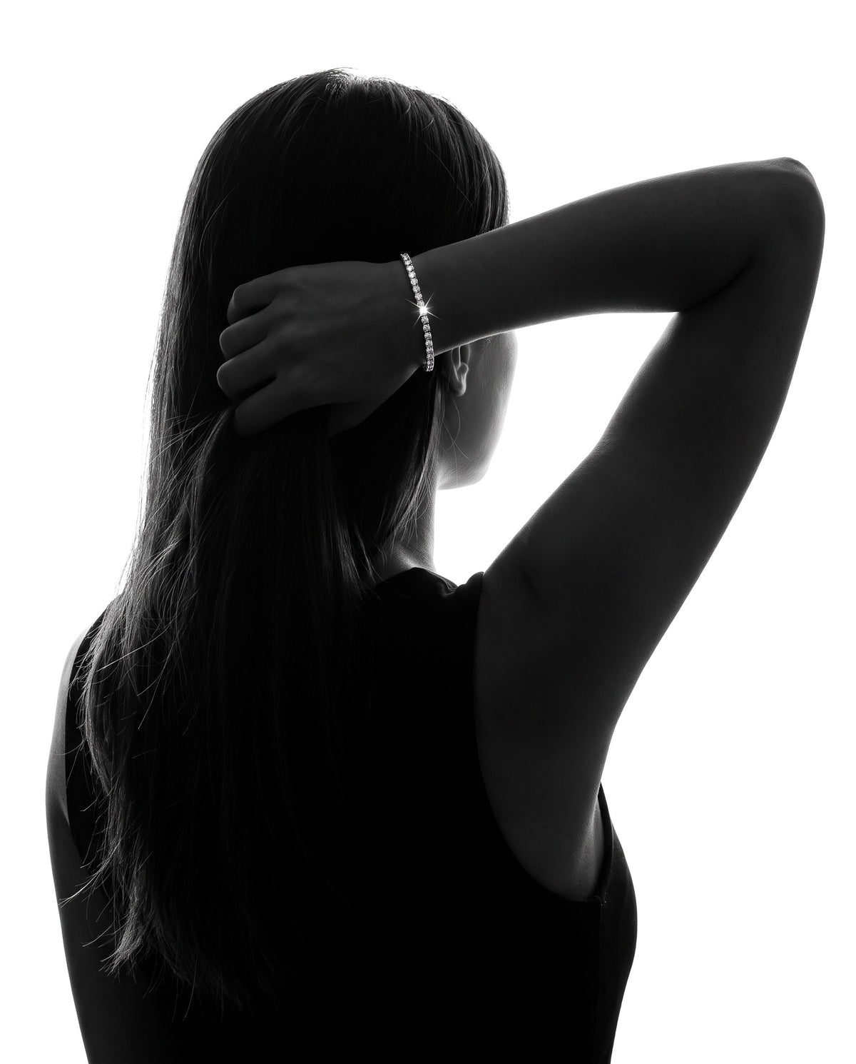 Woman tucking her hair behind her ear, wearing a 2mm lab-grown moissanite tennis bracelet